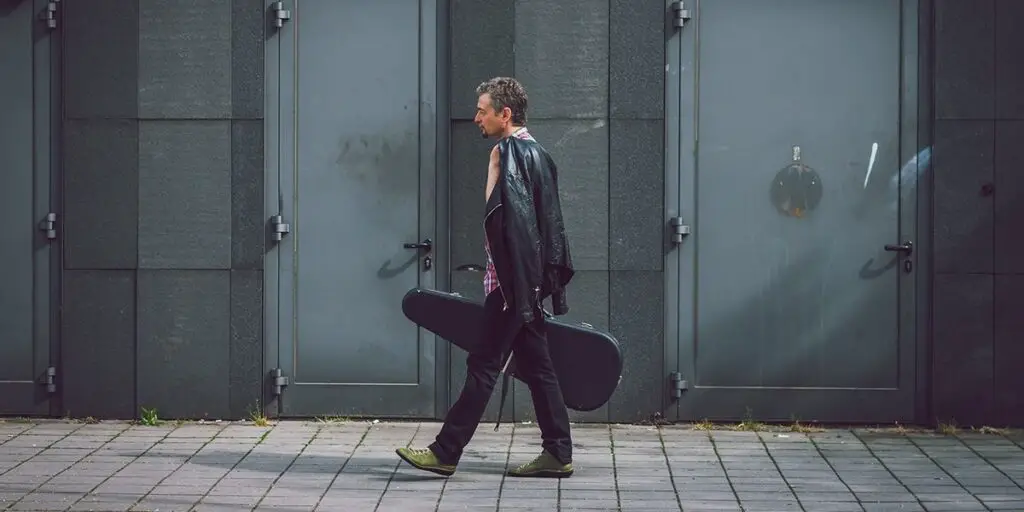 a guitar player walking with his guitar